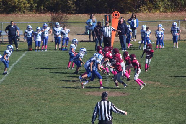 Football player in silver uniform runs with ball on a green field.