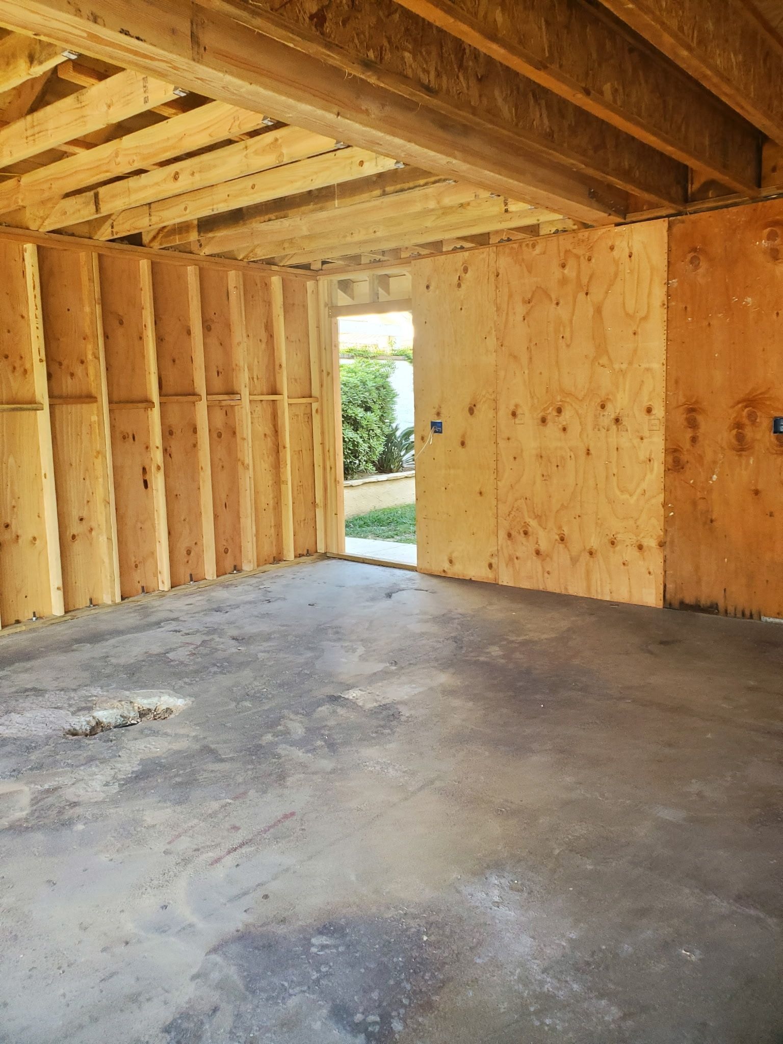 An empty room with wooden walls and a concrete floor.