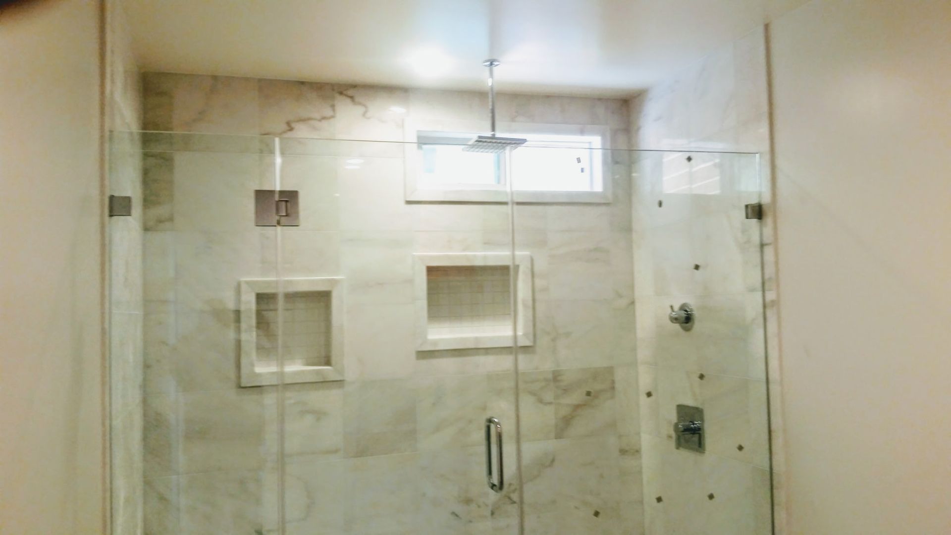 A bathroom with a glass shower door and a window.