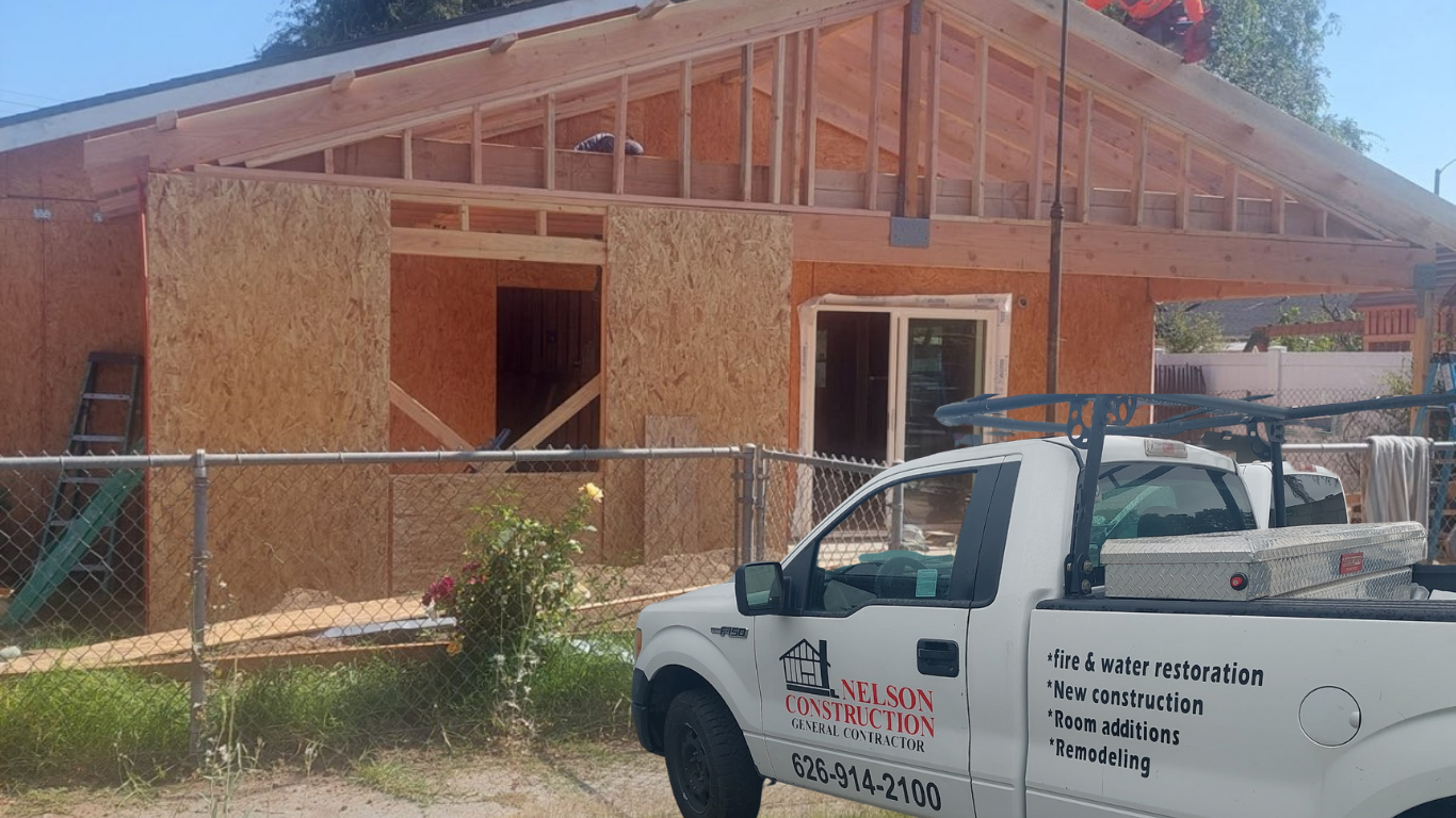 A white truck is parked in front of a house under construction.
