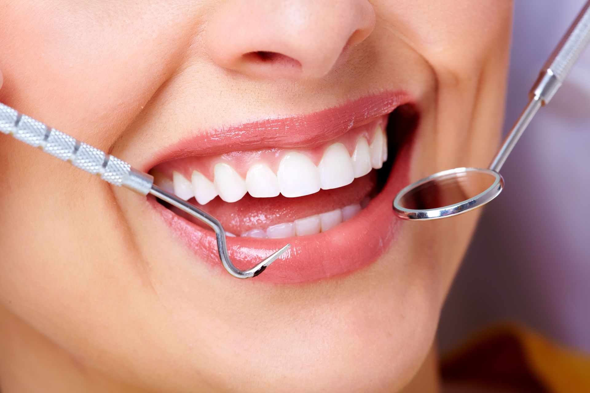 Woman with white teeth at a dental appointment; dental tools in view. Woman with white teeth at a dental appointment; dental tools in view.