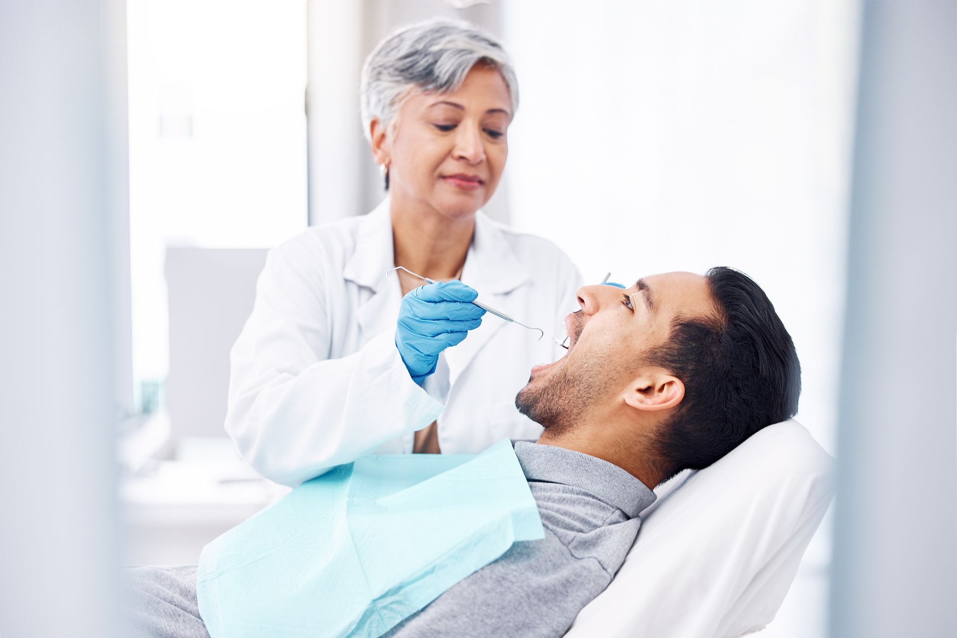 Woman, dentist and check teeth of man with tools for dental cosmetics, healthcare assessment and medical consulting.