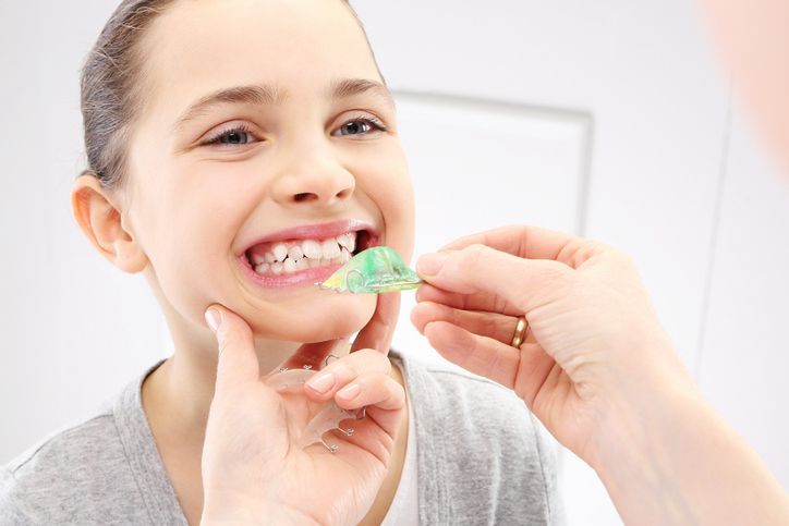 Child with orthodontic appliance showcasing cosmetic dentist care for aligned, healthy teeth.