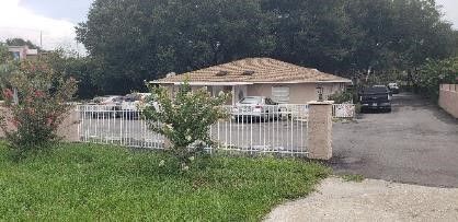 Two shrubs stand in front of a white fence. Central Florida Dental can be seen in the distance.