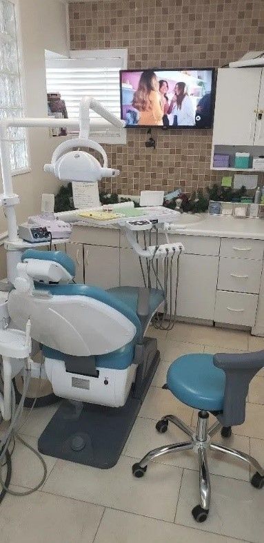 Doctor’s office with a blue and white patient chair, with a TV playing a show in front of it.