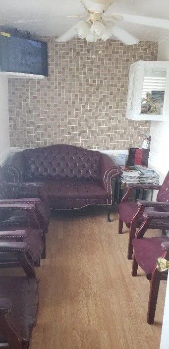 Picture of room with multicolored tiles on the walls, with a red sofa and red plush chairs.