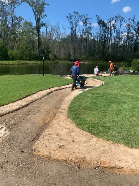 Workers constructing a dirt pathway next to a pond. 