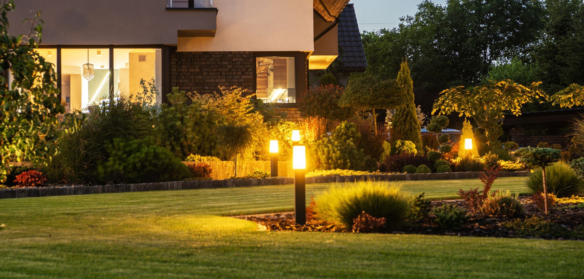A well-lit yard with a house at dusk.
