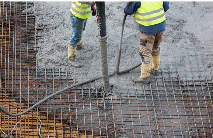 two concrete contractors pouring fresh concrete slab with rebar