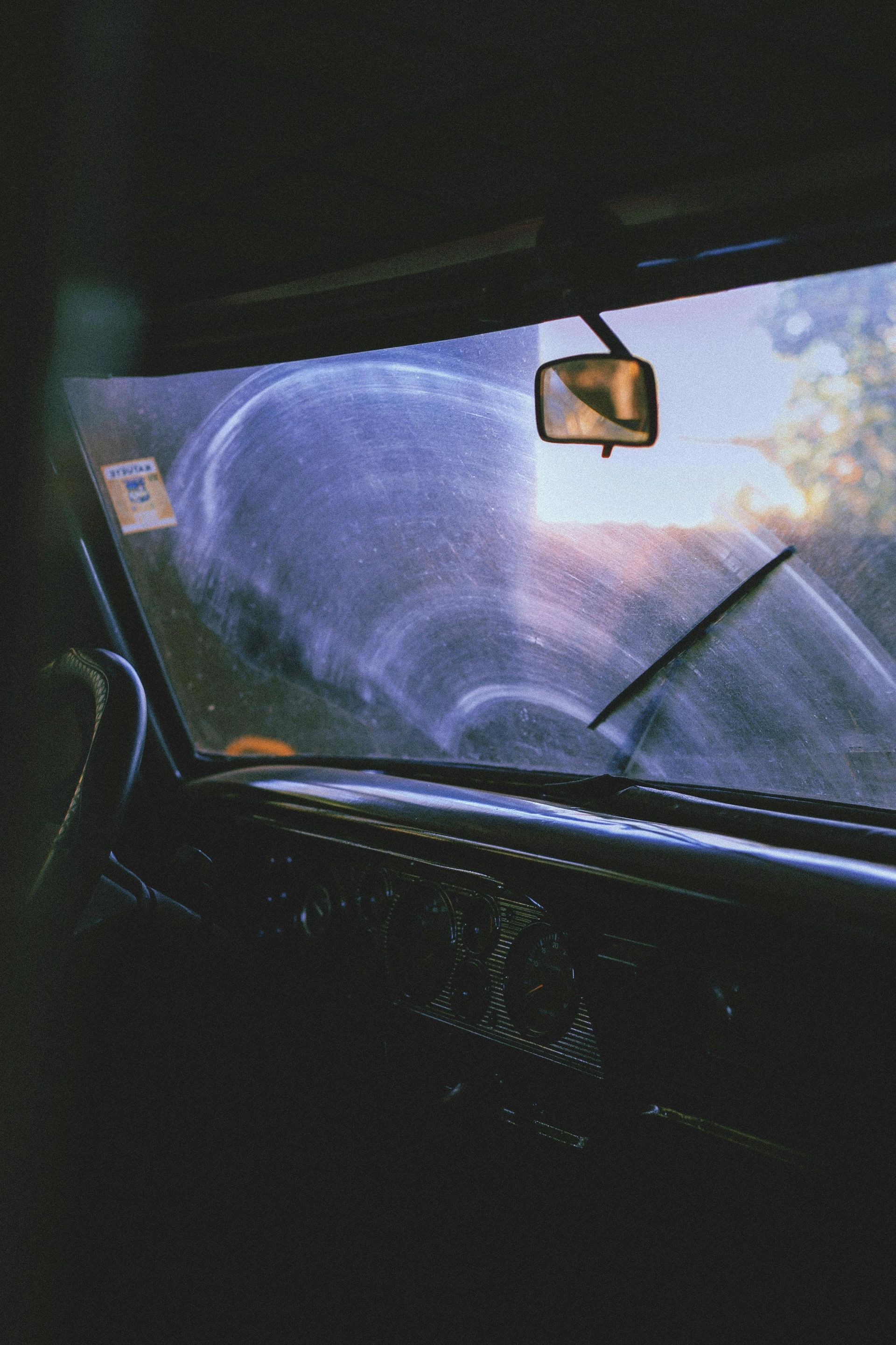Inside a car looking out at rain; windshield wipers clearing the glass.