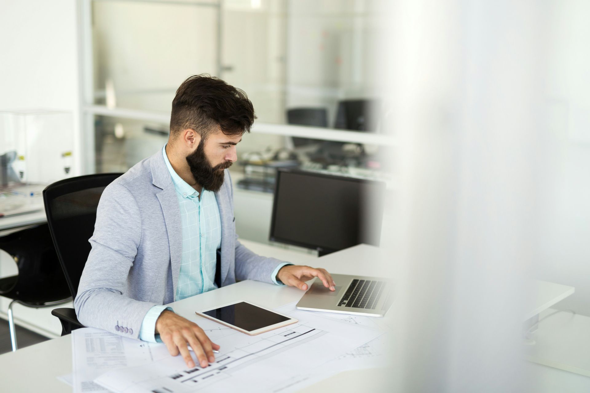 A man in a blue shirt and tie is using a laptop computer.