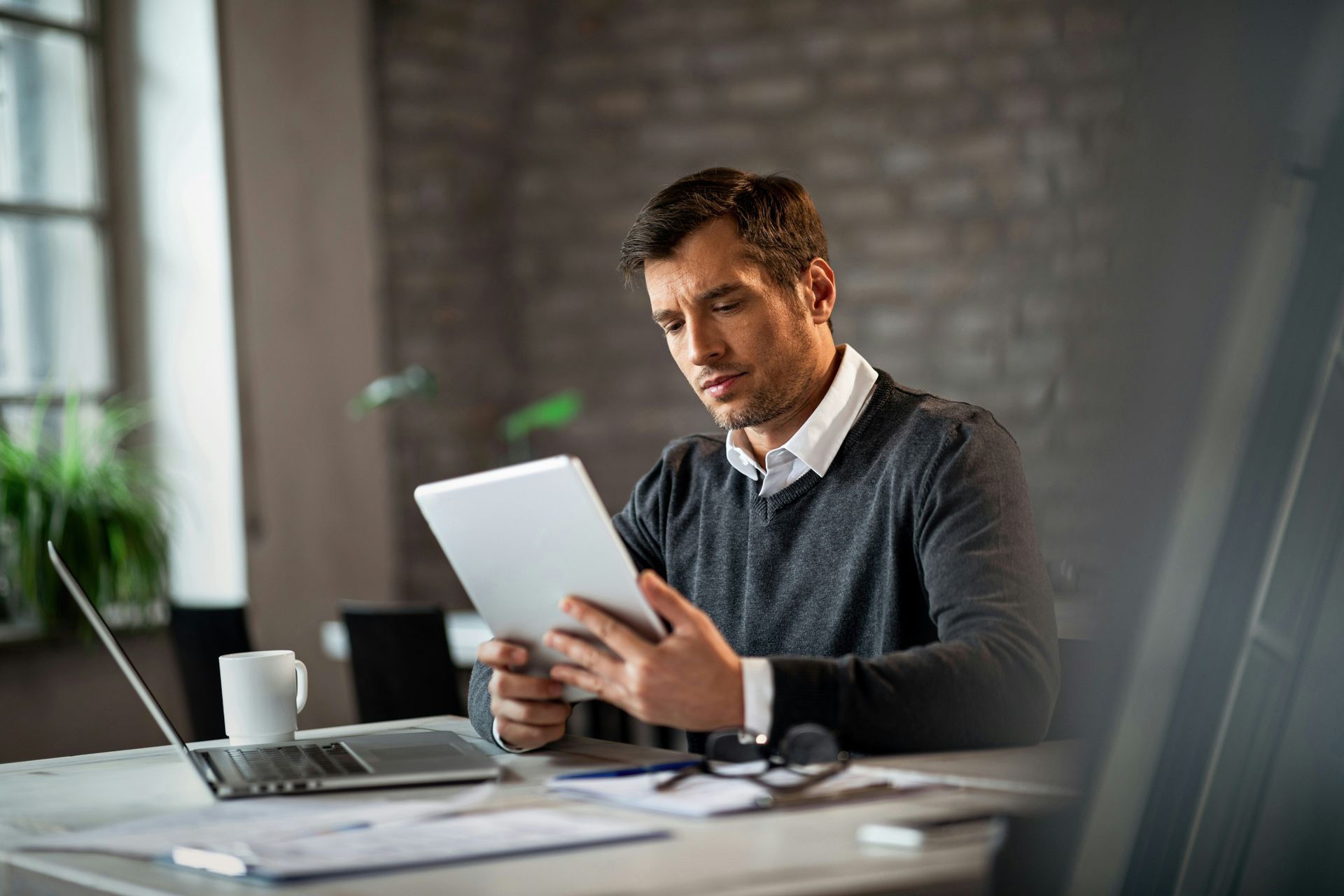 A man in a blue shirt and tie is using a laptop computer.