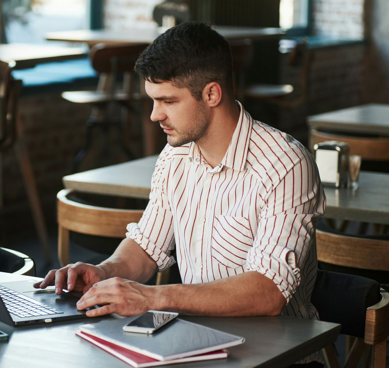 A man in a blue shirt and tie is using a laptop computer.