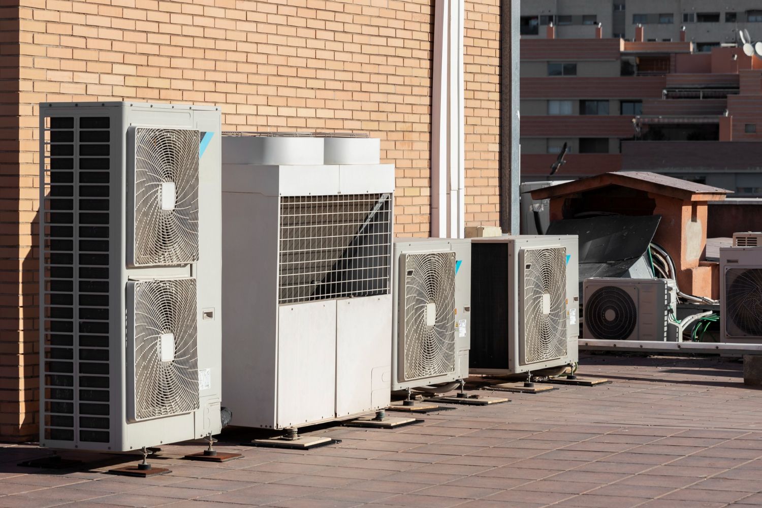 A row of air conditioners are sitting on top of a brick building.