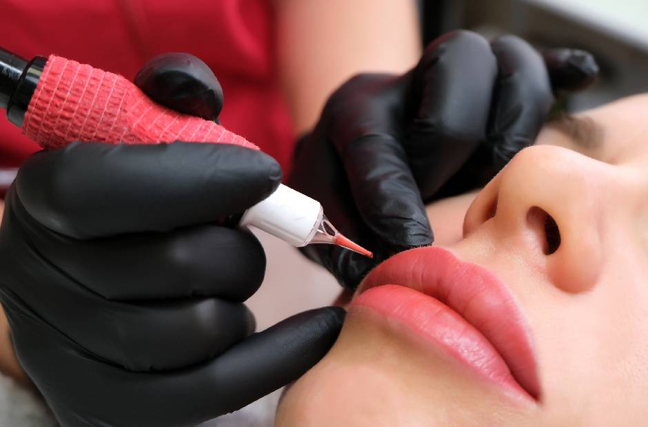 process woman applying permanent tattoo makeup on lips in beautician salon.