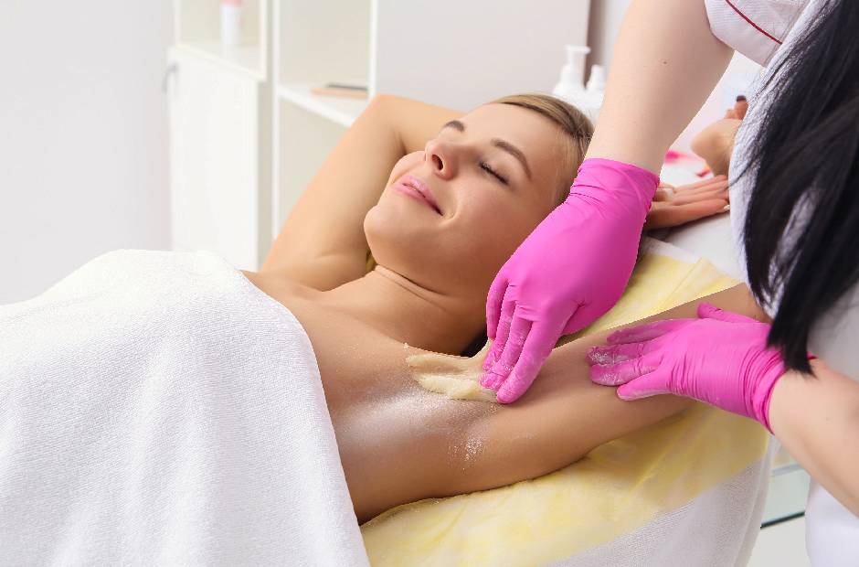beautician removing hair of young woman