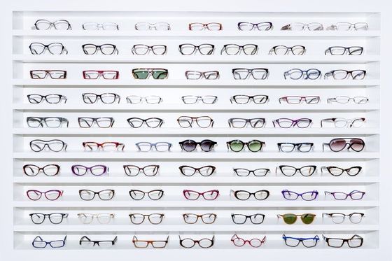 degli occhiali da vista di diversi colori in esposizione su un pannello