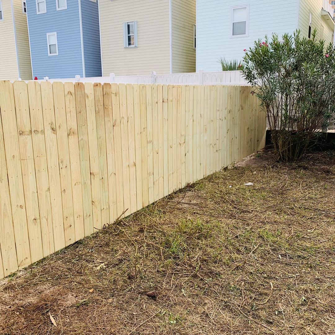 There is a wooden fence in the backyard of a house.