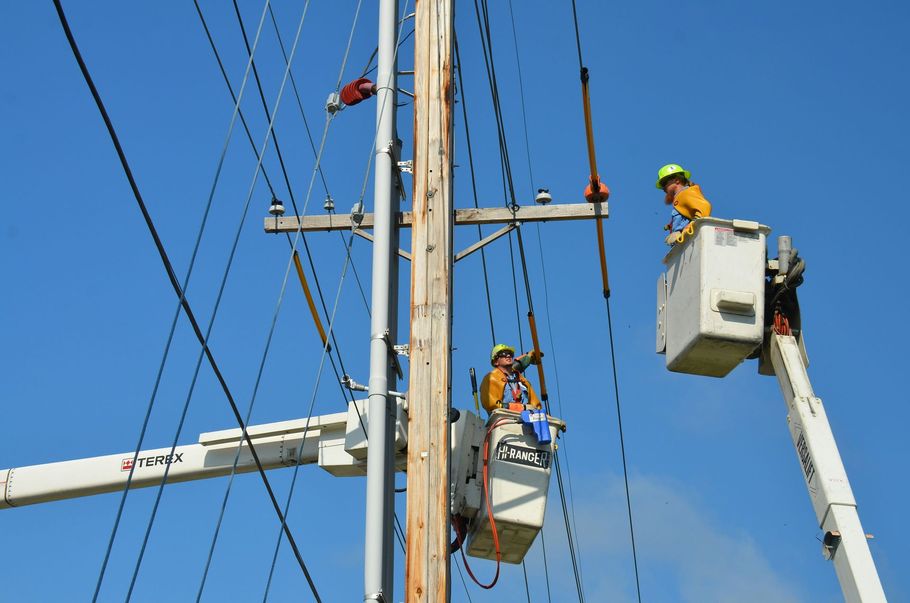 A person uses a screwdriver to install a double electrical wall outlet on a white wall.