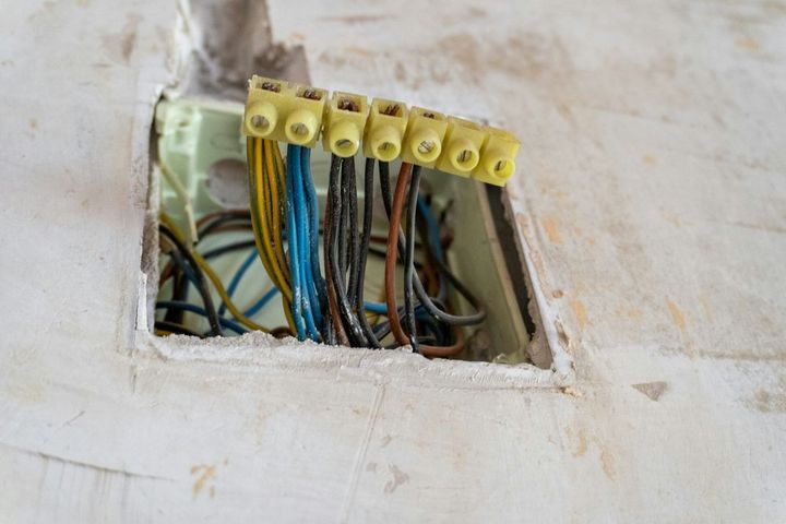 An open electrical junction box in a wall, containing several wires connected by a terminal block.