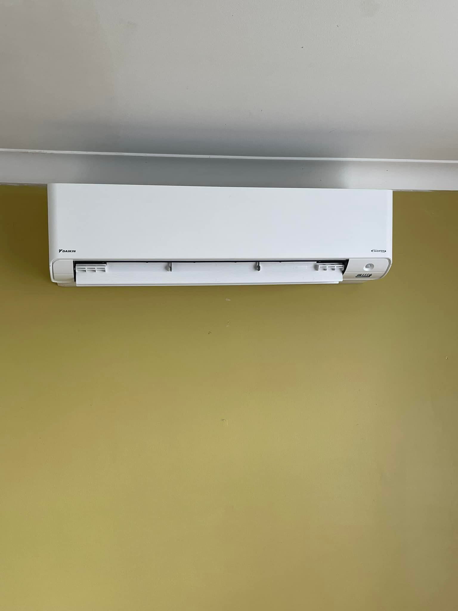 White Air Conditioning Unit Mounted on A Yellow Wall — Canobolas Air in Oberon, NSW