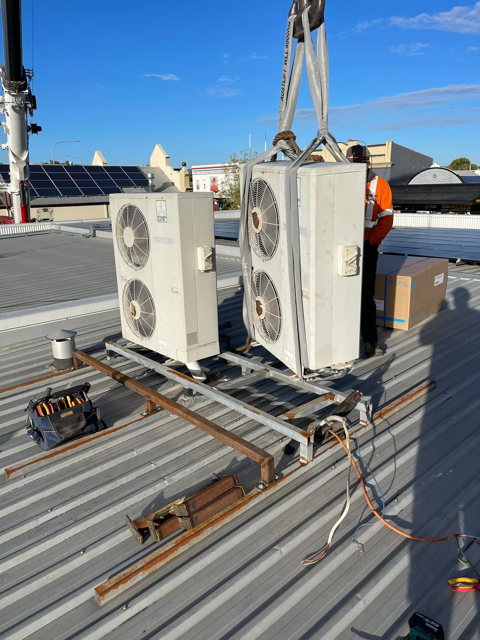 Two HVAC Units Being Lowered onto A Metal Rooftop by A Crane — Canobolas Air in Cowra, NSW