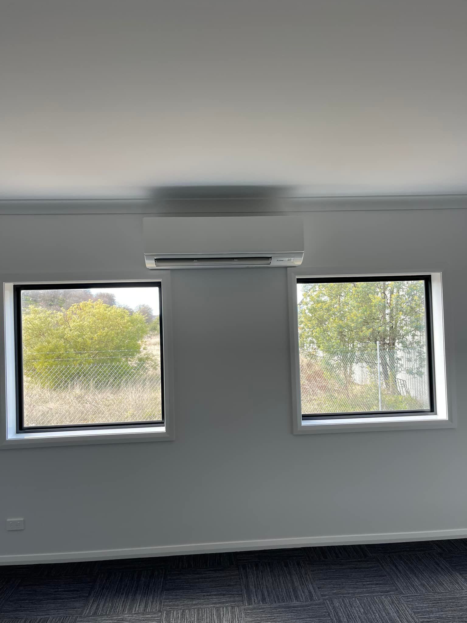 Interior Wall with Two Windows Flanking an Air Conditioning Unit — Canobolas Air in Mudgee, NSW