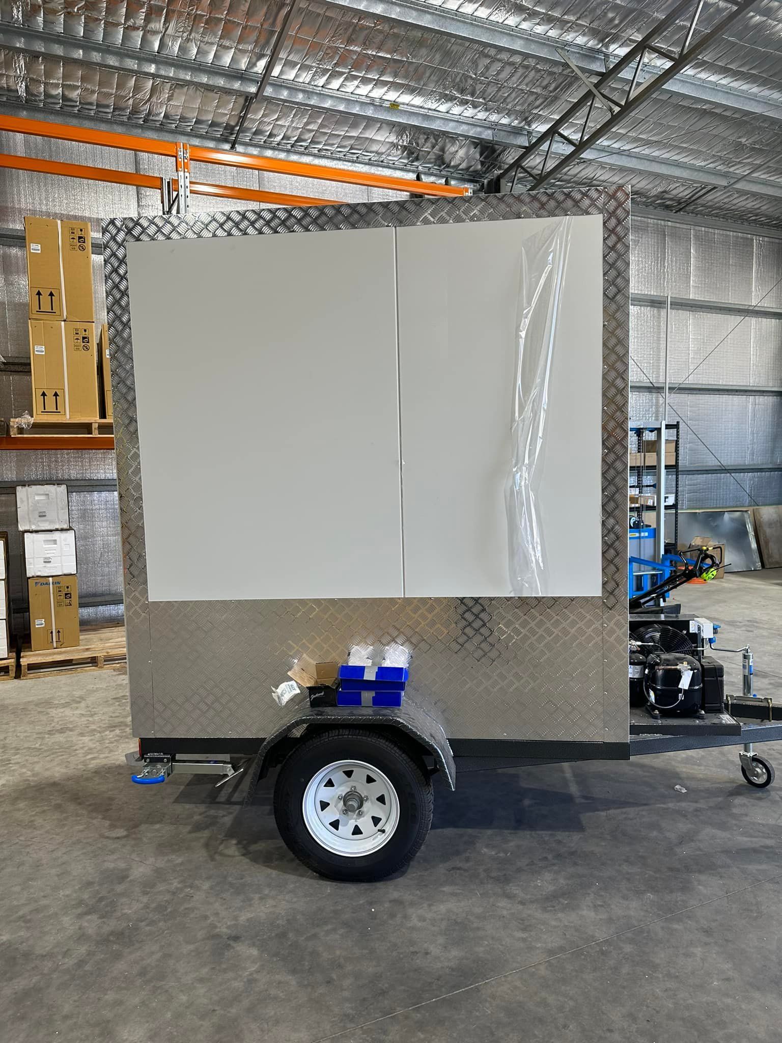A White Sign Trailer with A Metal Frame, Wheel, and Boxes in A Warehouse — Canobolas Air in Cowra, NSW