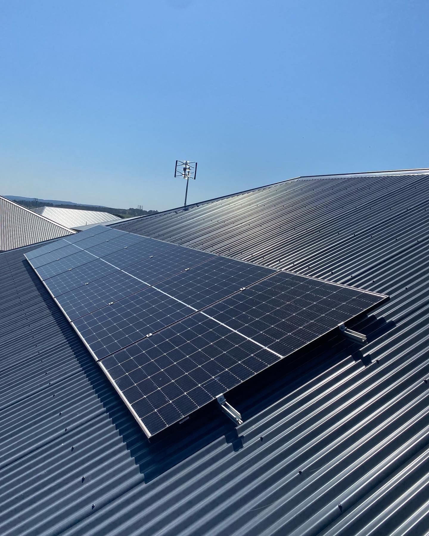 Solar Panels Installed on A Corrugated Metal Roof Under a Blue Sky — Canobolas Air in Orange, NSW