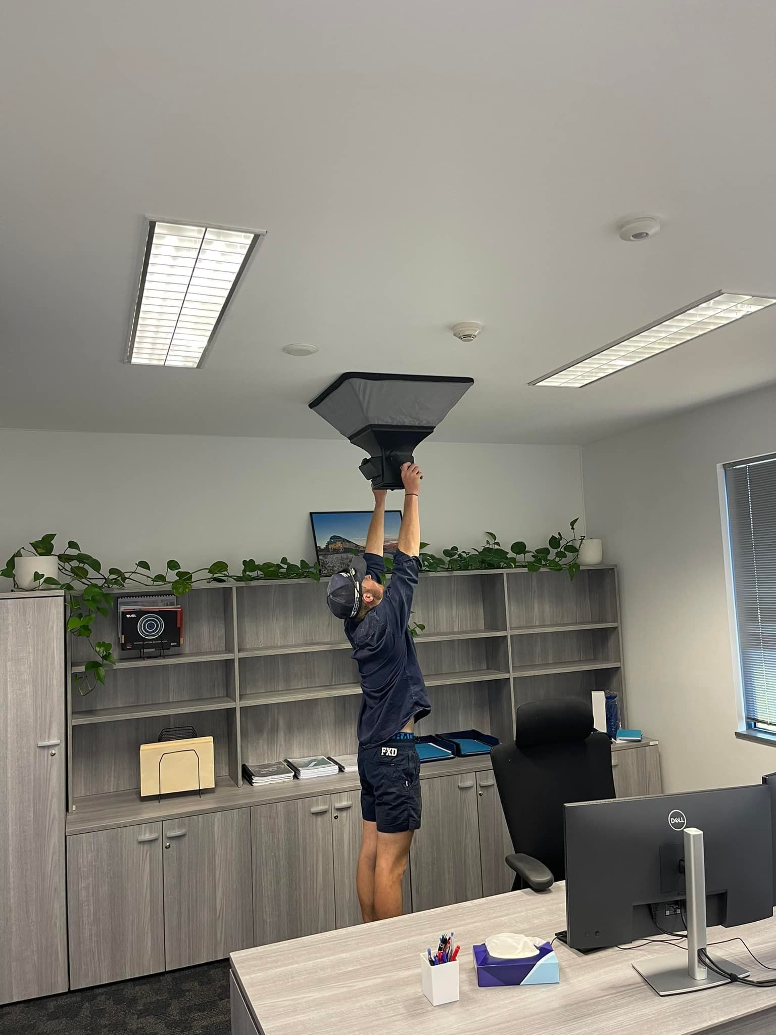 Person Installing a Ceiling Fixture in An Office — Canobolas Air in Orange, NSW
