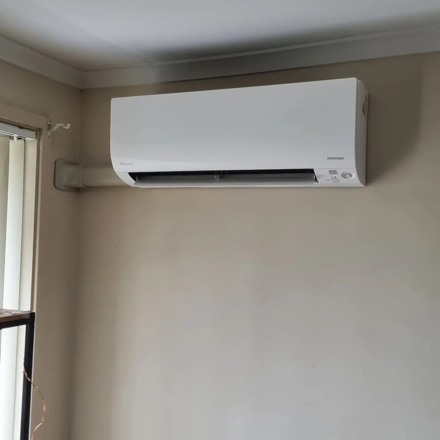 White Air Conditioning Unit Mounted on A Beige Wall in A Corner of A Room — Canobolas Air in Orange, NSW