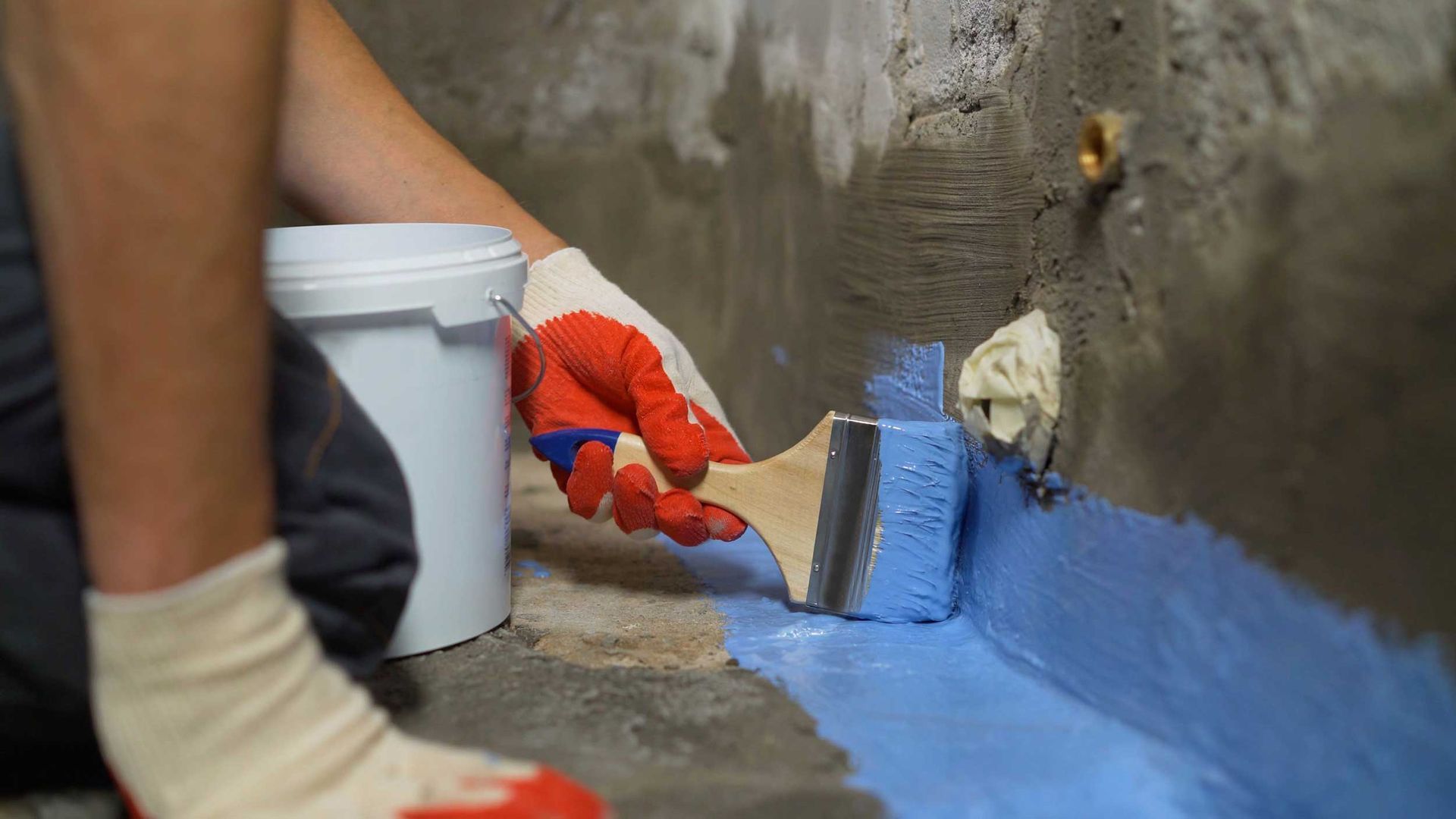 Applying blue coating for basement waterproofing.