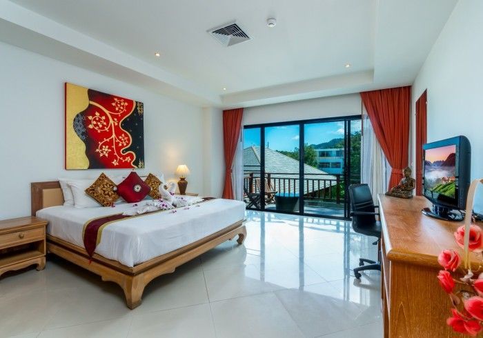 Hotel bedroom with king bed, balcony view, and red accents.