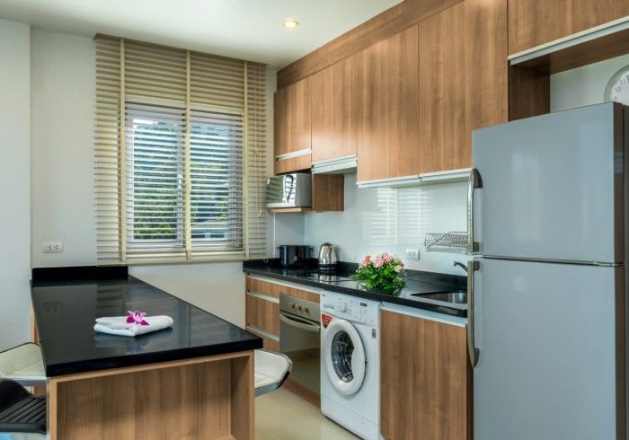 Kitchen with dark countertop, wood cabinets, window, appliances, and a washing machine.