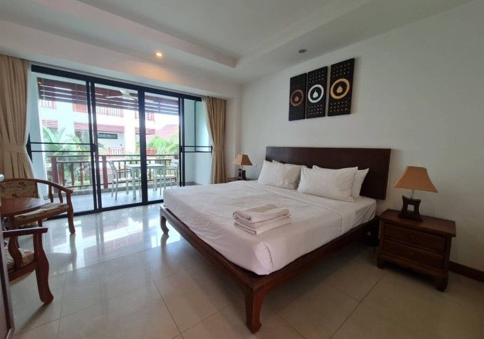 Bedroom with a bed, nightstand, lamps, and balcony access.  Neutral tones, decorative wall art.