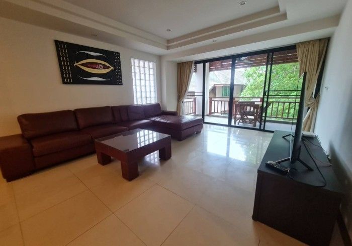 Living room with brown leather sectional sofa, sliding glass door, and a TV.
