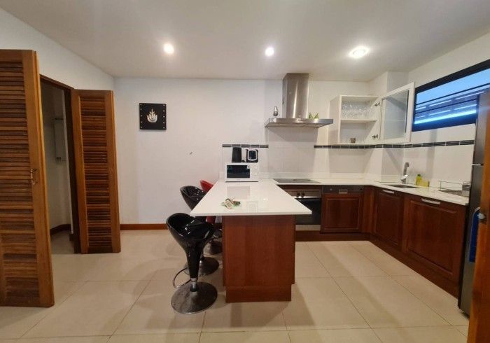 Kitchen with brown cabinetry, white countertops, and a central island with bar stools.