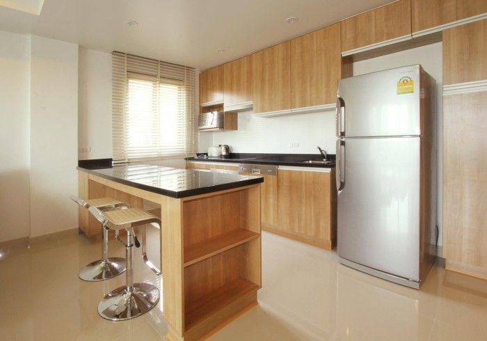 Kitchen with wooden cabinets, a stainless steel refrigerator, and a breakfast bar with stools.