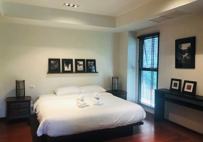 Bedroom with a bed, nightstands, artwork, and a window with blinds.