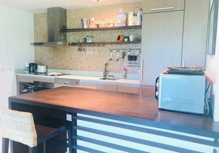Modern kitchen with dark wood island, stainless steel appliances, and mosaic backsplash.