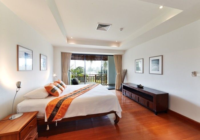 Bright bedroom with a bed, dresser, balcony, and hardwood floor.