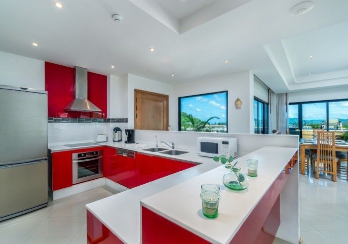 Modern kitchen with red cabinets, stainless steel appliances, and a countertop bar.