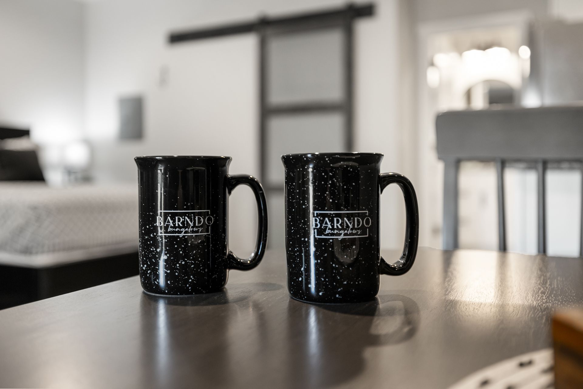 Two coffee mugs are sitting on a table in a hotel room.
