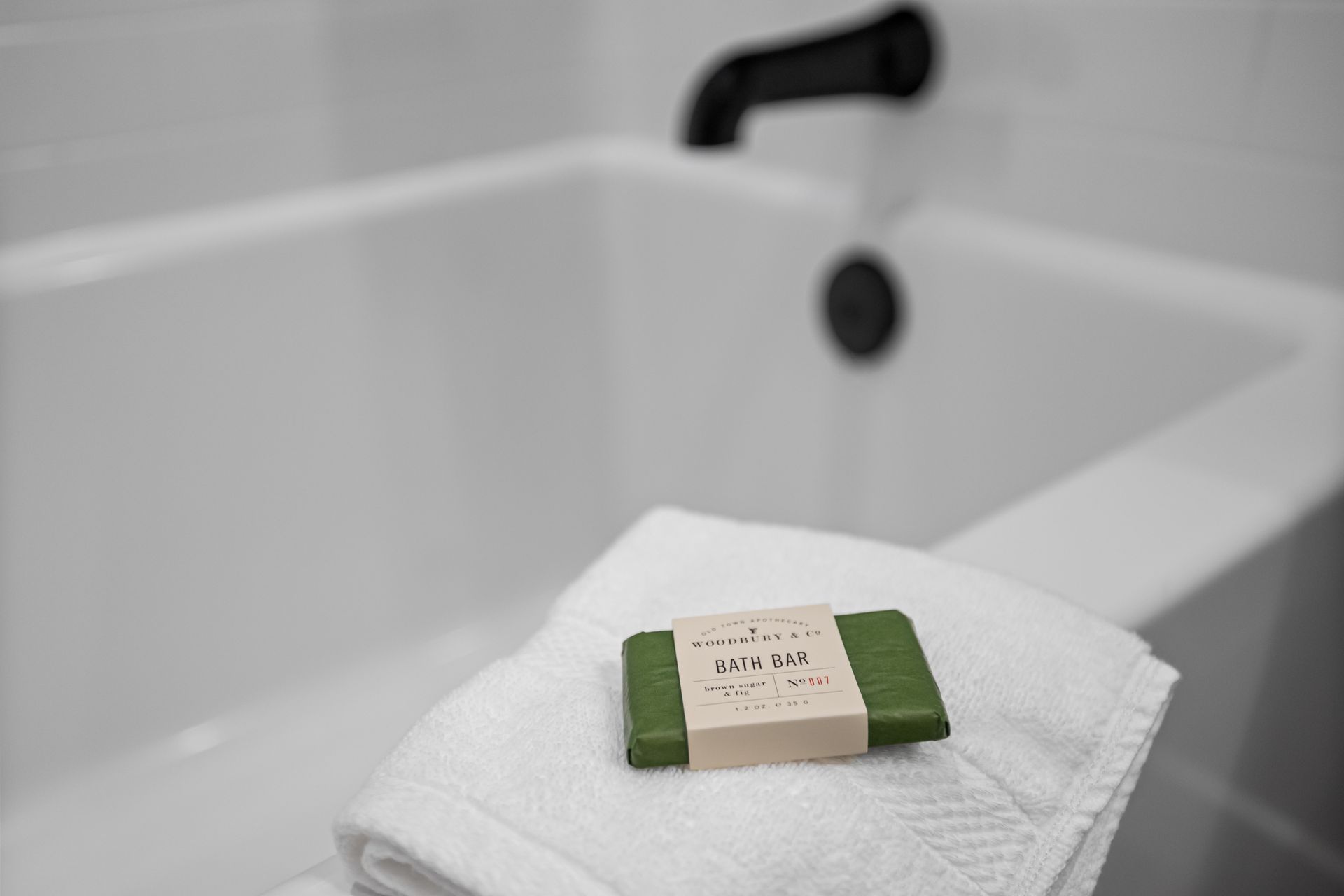 A bar of soap is sitting on a towel next to a bathtub.