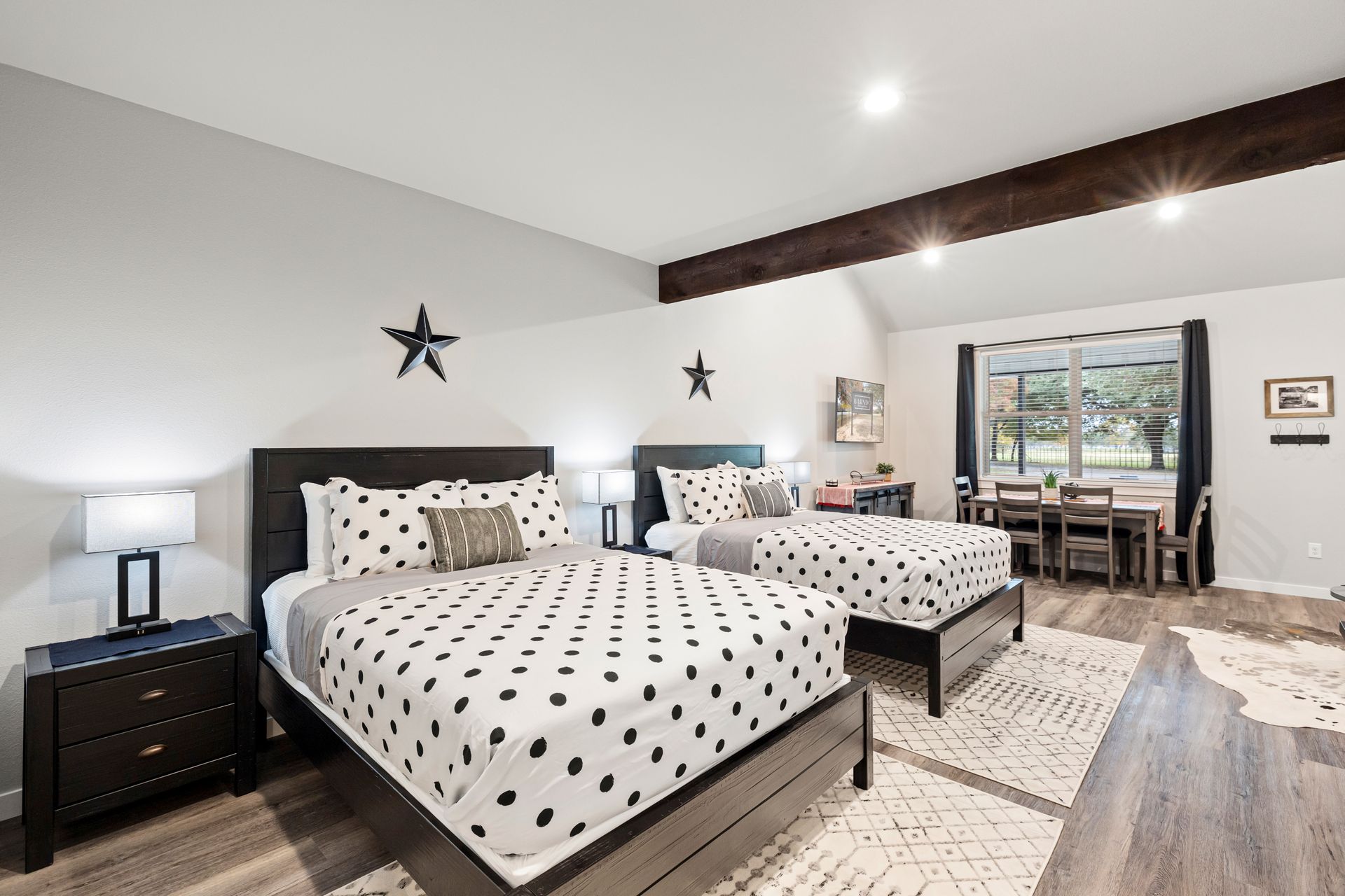 A bedroom with two beds , a nightstand , a desk and a window.