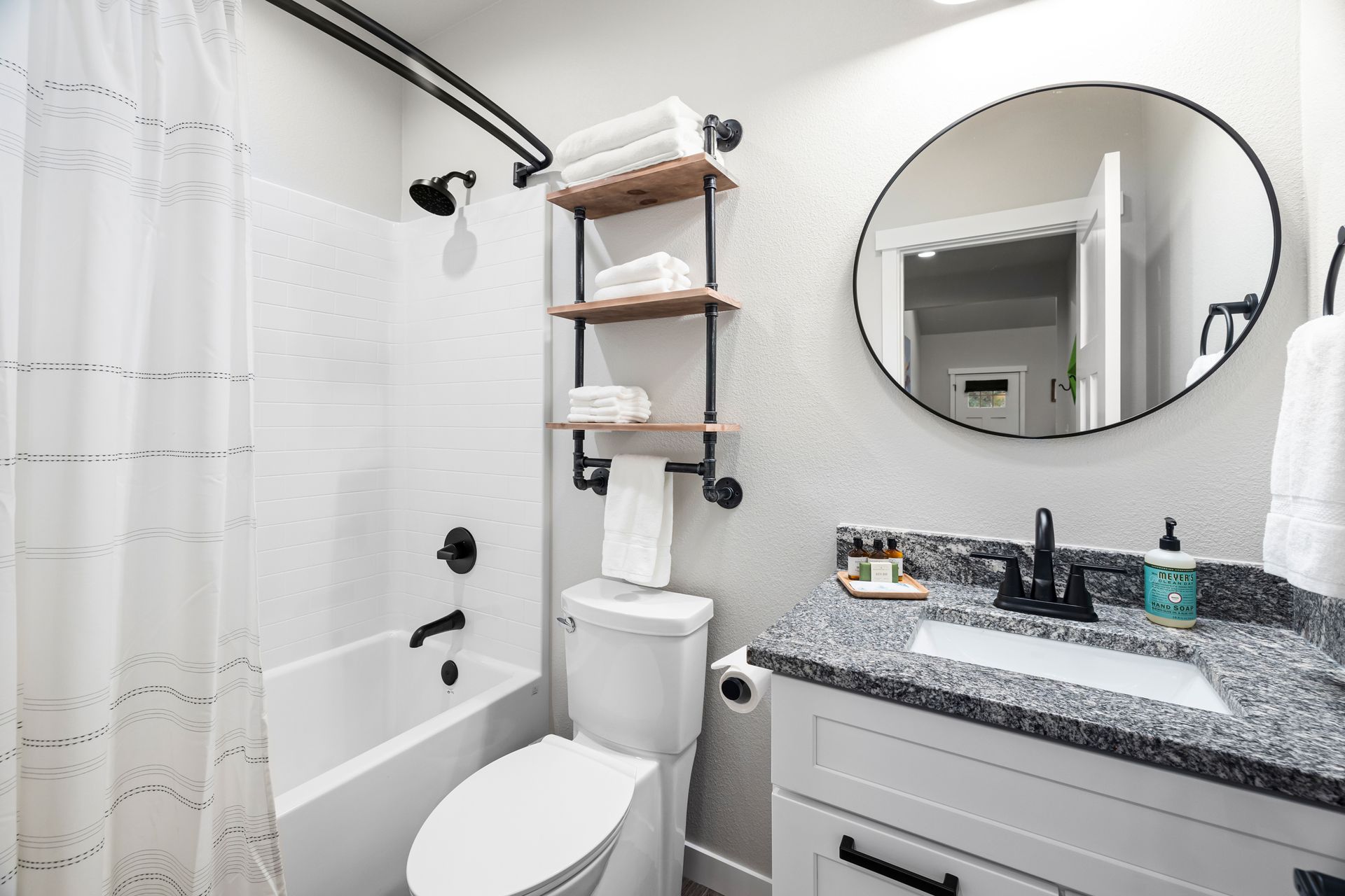 A bathroom with a toilet , sink , bathtub and mirror.