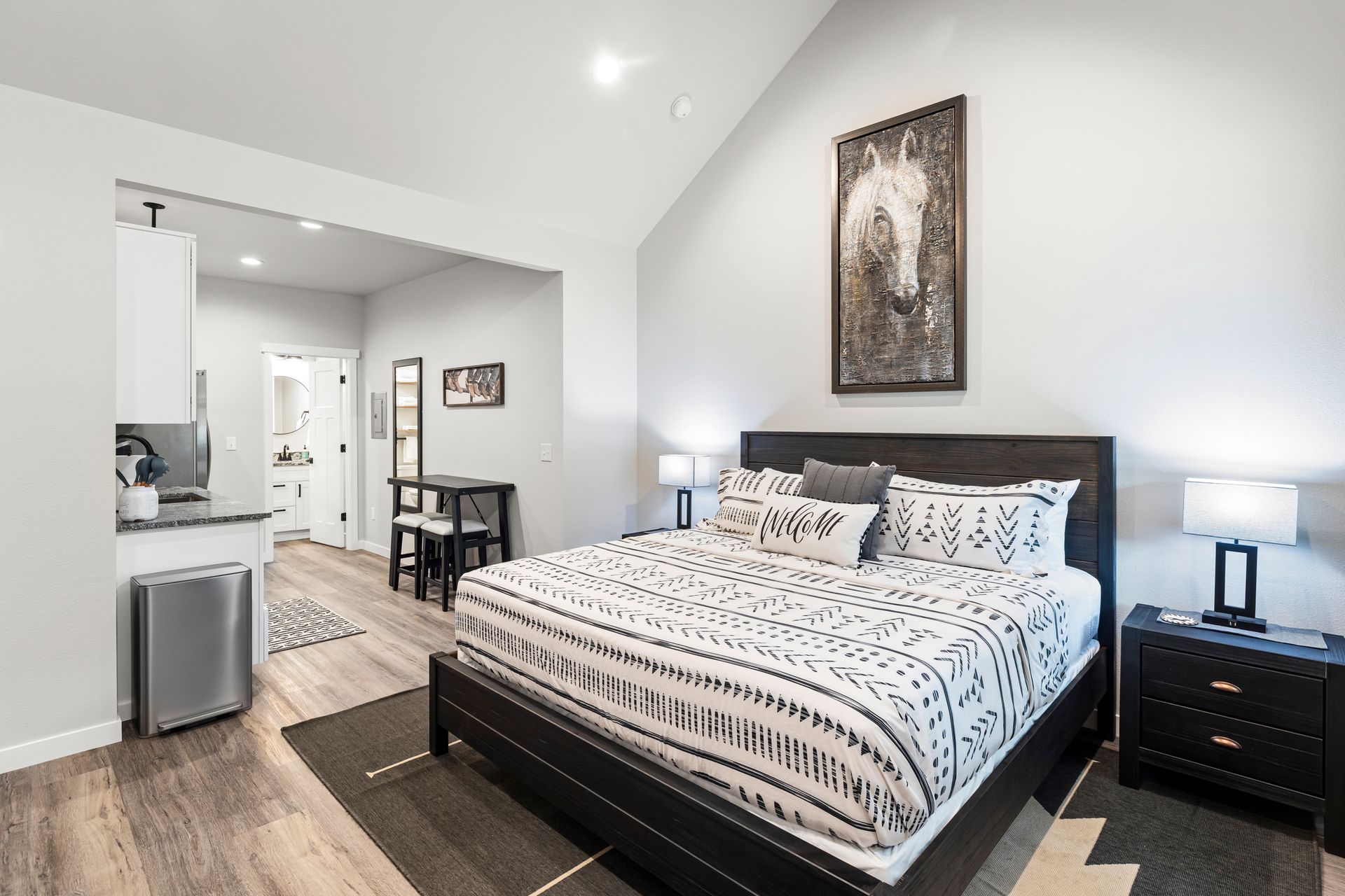 A bedroom with a king size bed and a painting of a horse on the wall.