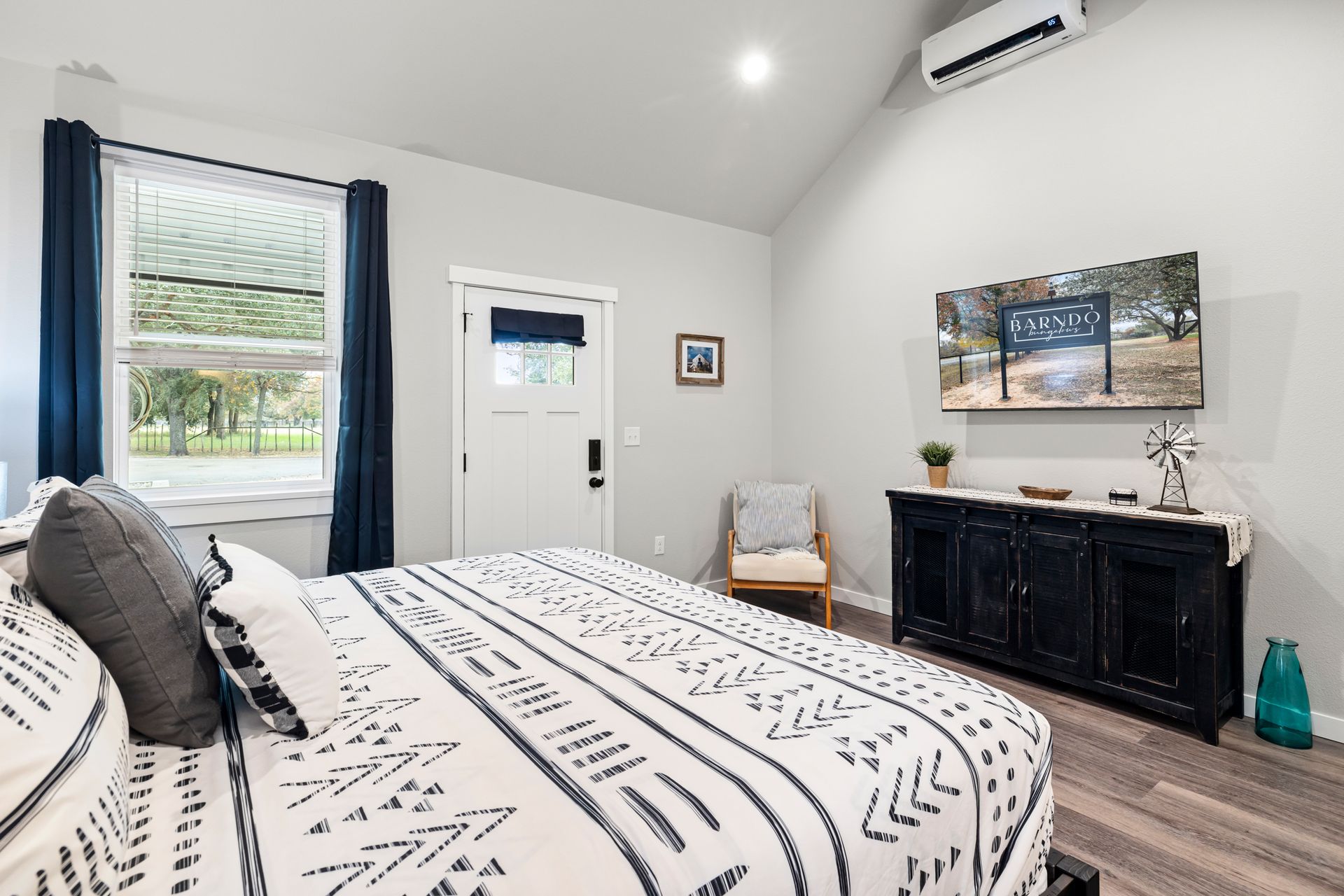 A bedroom with a large bed , dresser , chair and window.
