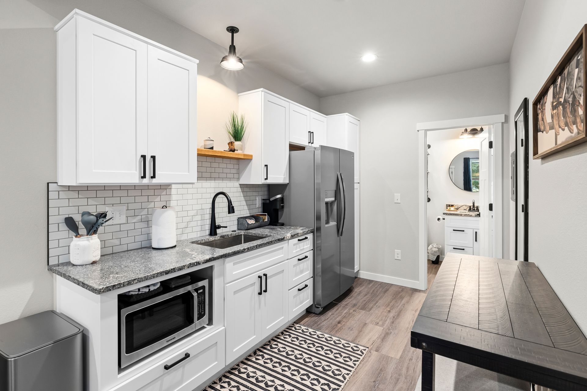 A kitchen with white cabinets , granite counter tops , stainless steel appliances , and a refrigerator.