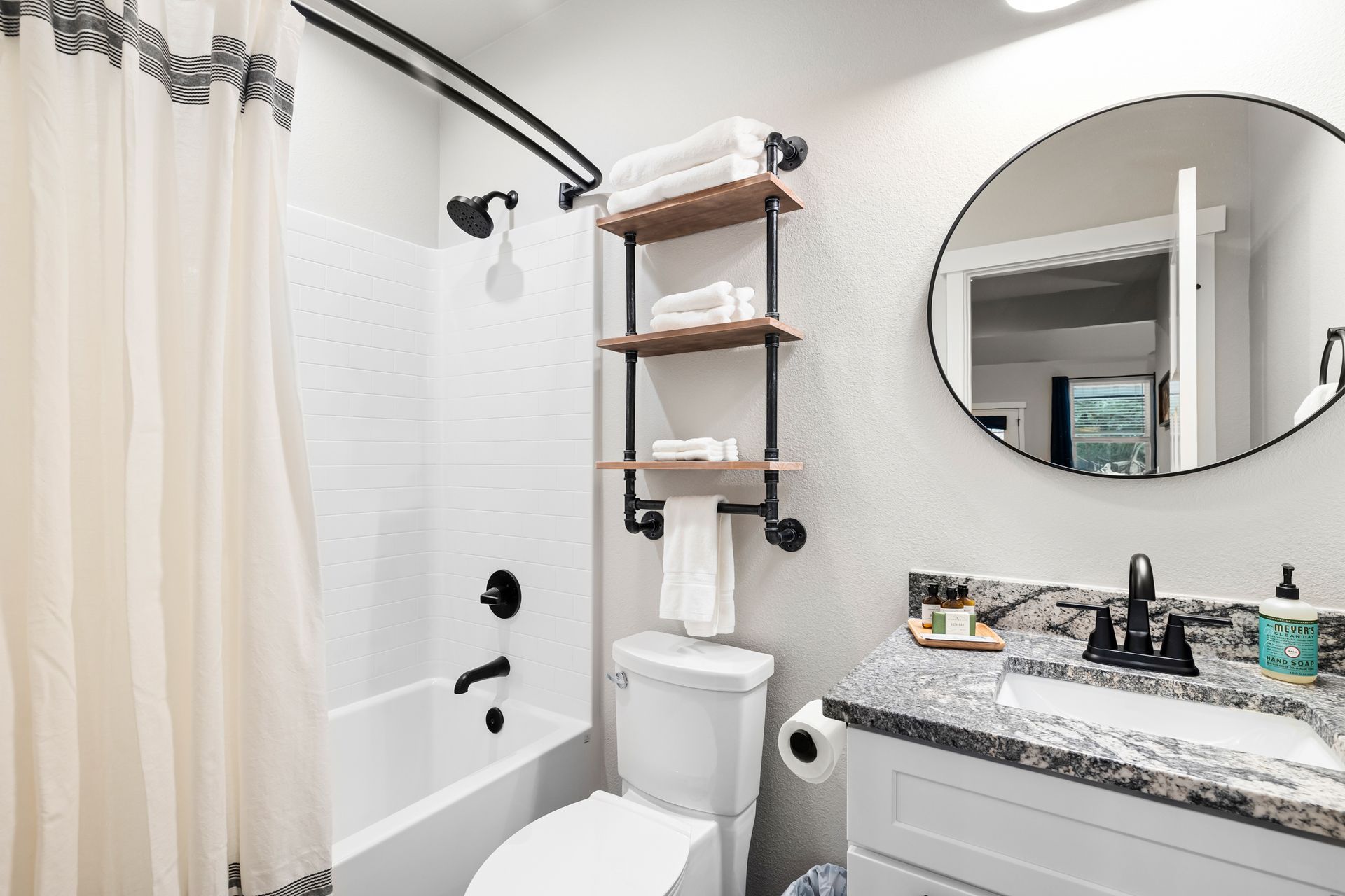 A bathroom with a toilet , sink , shower and mirror.